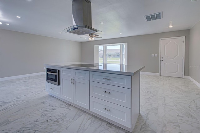 kitchen featuring island exhaust hood, marble finish floor, black electric stovetop, and visible vents