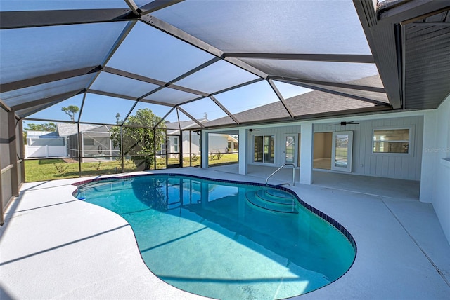 view of swimming pool featuring ceiling fan, a yard, glass enclosure, and a patio