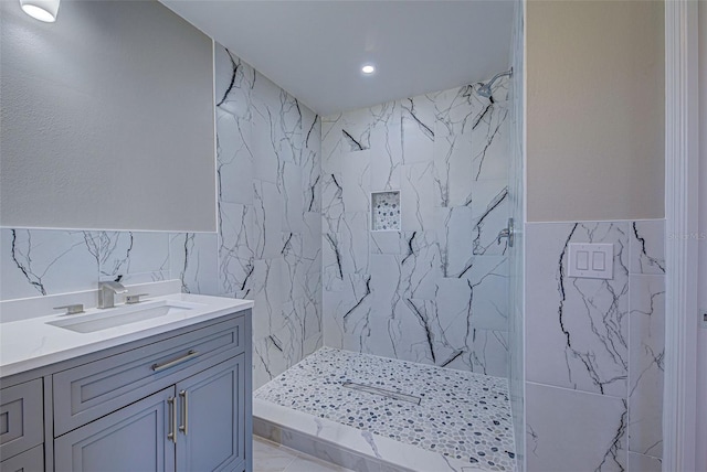 bathroom featuring recessed lighting, tile walls, a marble finish shower, and vanity
