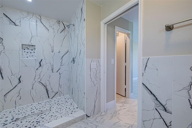 bathroom featuring a wainscoted wall, a tile shower, and marble finish floor