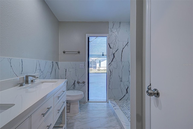 bathroom with a sink, toilet, a marble finish shower, marble finish floor, and tile walls