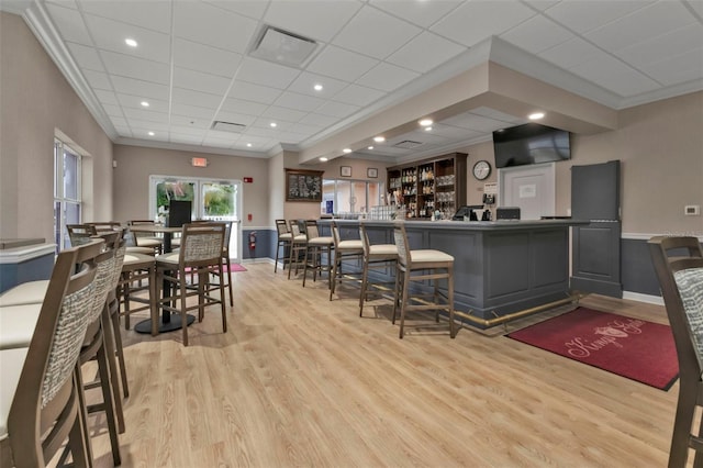 dining area featuring ornamental molding, light wood-type flooring, and bar