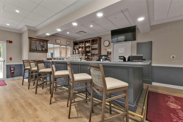 bar with gray cabinets, light wood-type flooring, crown molding, and a paneled ceiling