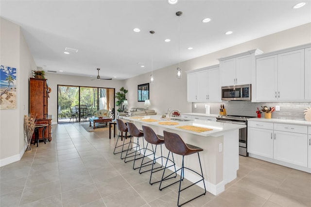 kitchen with appliances with stainless steel finishes, white cabinetry, and an island with sink