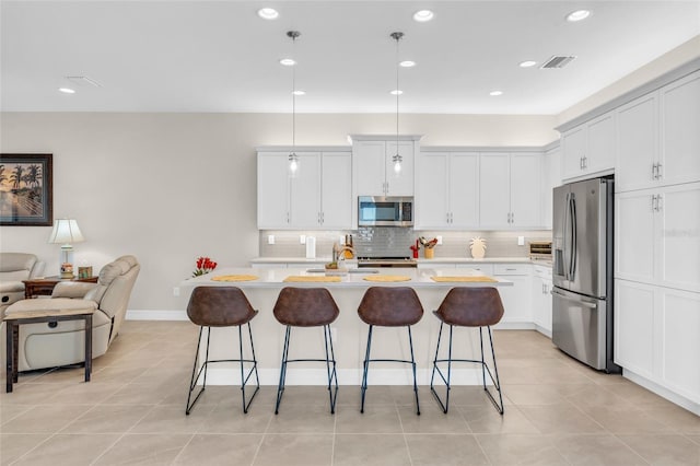 kitchen with white cabinetry, appliances with stainless steel finishes, a breakfast bar, and a center island with sink