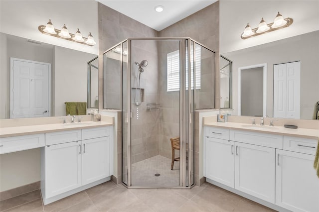 bathroom with a shower with door, vanity, and tile patterned floors