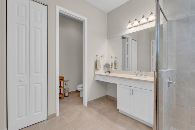 bathroom featuring vanity, a tile shower, toilet, and tile patterned floors