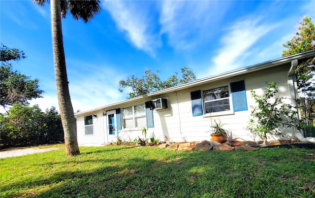 ranch-style house with a wall unit AC and a front lawn