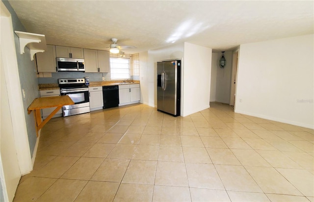 kitchen featuring ceiling fan, sink, light tile patterned floors, and stainless steel appliances