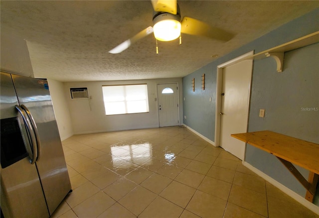 interior space with a wall unit AC, ceiling fan, light tile patterned floors, and a textured ceiling