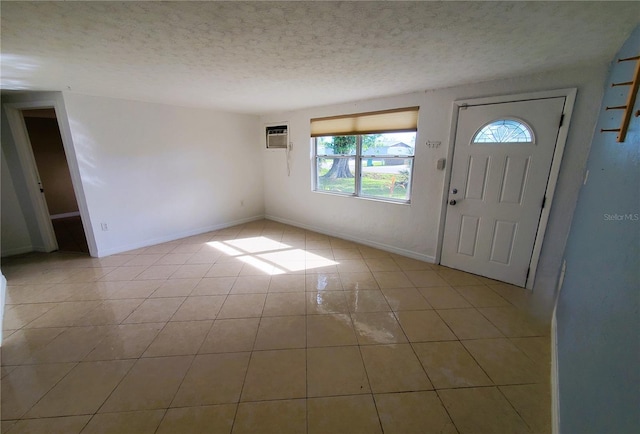 foyer with a wall unit AC, light tile patterned floors, and a textured ceiling