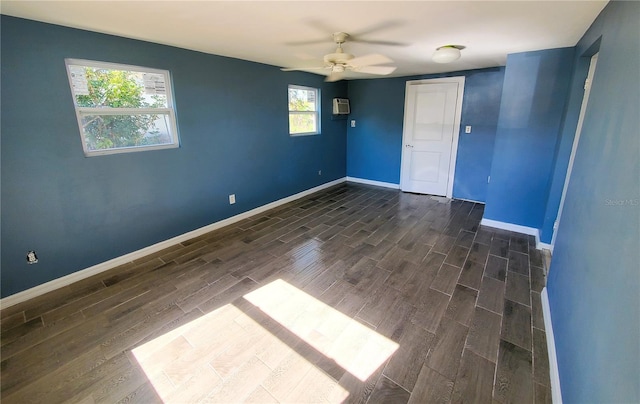 empty room featuring dark hardwood / wood-style flooring, a wall unit AC, and ceiling fan