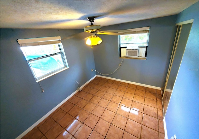 tiled empty room with ceiling fan, cooling unit, a textured ceiling, and vaulted ceiling