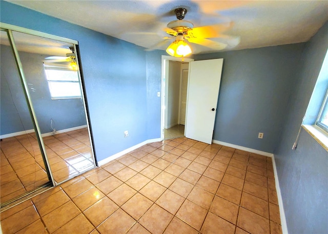 unfurnished bedroom with ceiling fan, light tile patterned floors, and a closet