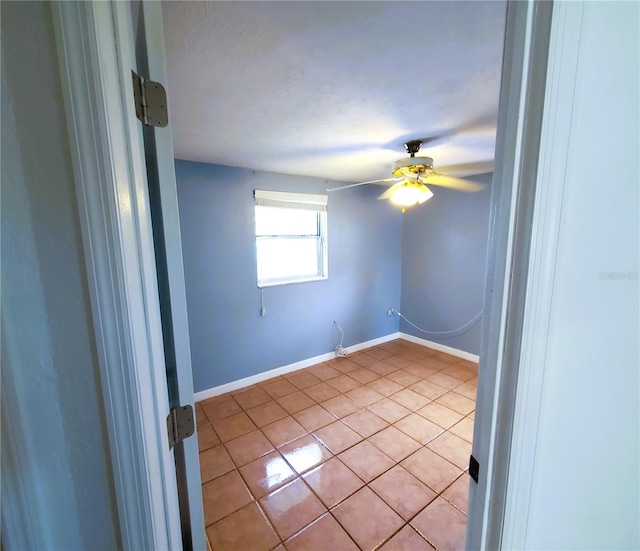 tiled spare room with ceiling fan