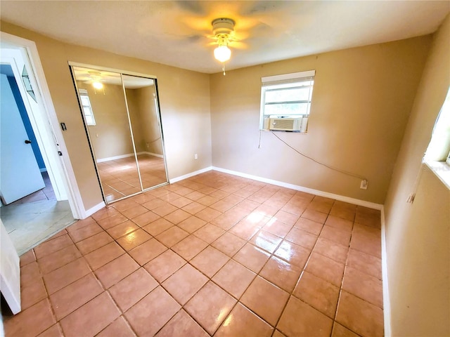 unfurnished bedroom with ceiling fan, light tile patterned flooring, a closet, and cooling unit