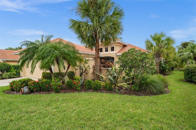 mediterranean / spanish home featuring a front yard and a garage