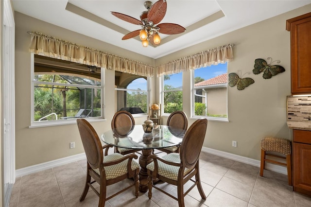 dining area with light tile patterned floors, a tray ceiling, and ceiling fan