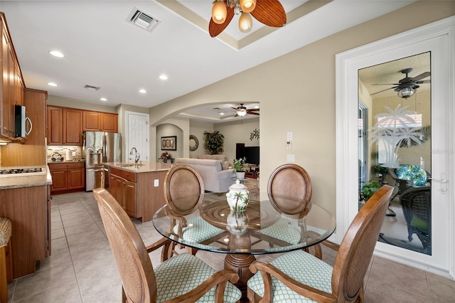 dining area with light tile patterned flooring, sink, and a raised ceiling