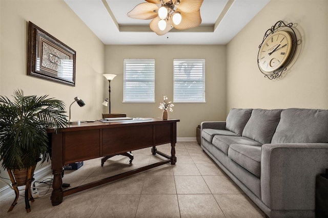 office featuring light tile patterned floors, a tray ceiling, and ceiling fan