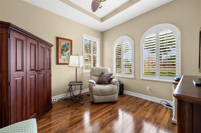 sitting room with a tray ceiling, dark wood-type flooring, and ceiling fan