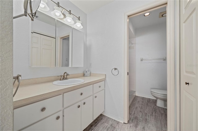 bathroom featuring toilet, vanity, wood-type flooring, and a shower