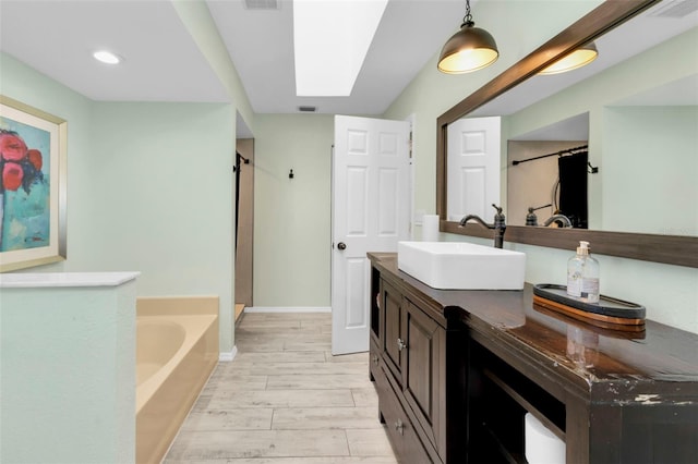 bathroom featuring hardwood / wood-style floors, vanity, a tub to relax in, and a skylight