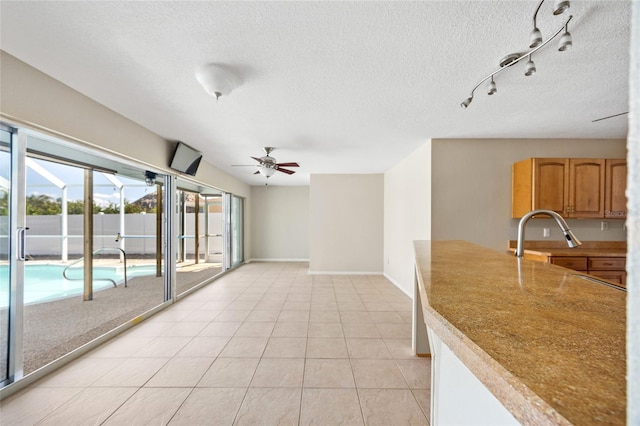 interior space featuring sink, light tile patterned flooring, a textured ceiling, and ceiling fan