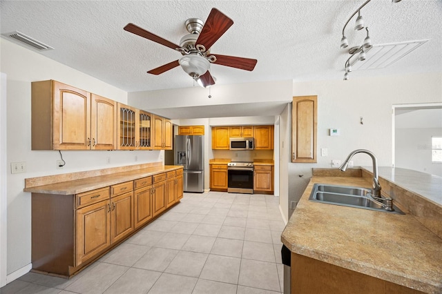 kitchen featuring ceiling fan, appliances with stainless steel finishes, light tile patterned floors, a textured ceiling, and sink