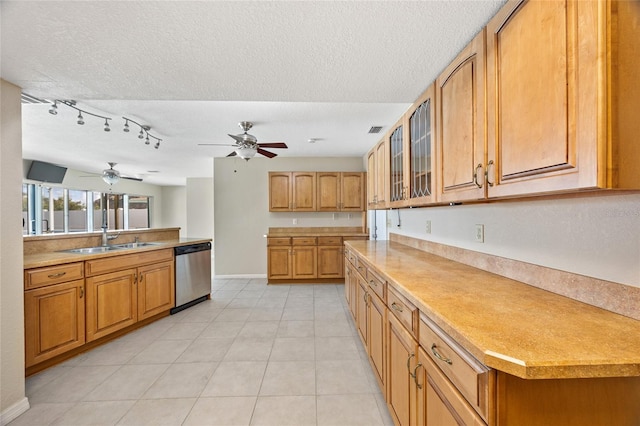 kitchen featuring sink, light tile patterned floors, stainless steel dishwasher, a textured ceiling, and ceiling fan