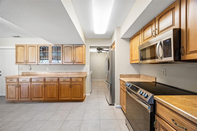 kitchen with ceiling fan, stainless steel appliances, a textured ceiling, and light tile patterned flooring