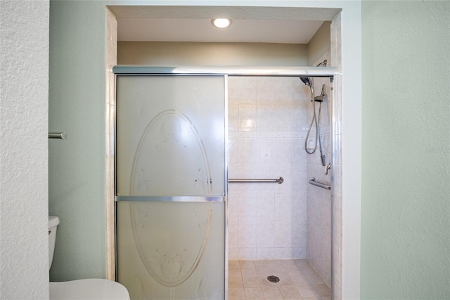 bathroom featuring toilet and a shower with door