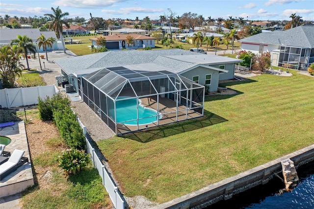 view of swimming pool featuring a patio, a water view, a lawn, and a lanai