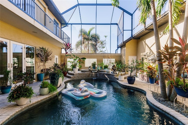 view of pool featuring pool water feature, a patio area, glass enclosure, and a jacuzzi