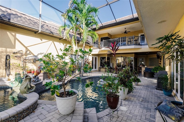 view of patio with a balcony, glass enclosure, and ceiling fan