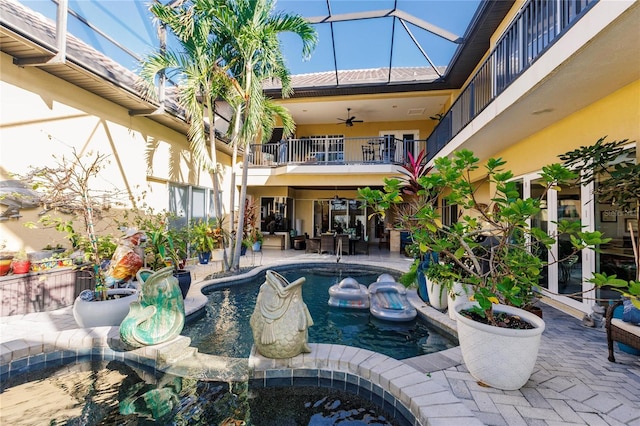 view of pool with a patio area, glass enclosure, and ceiling fan