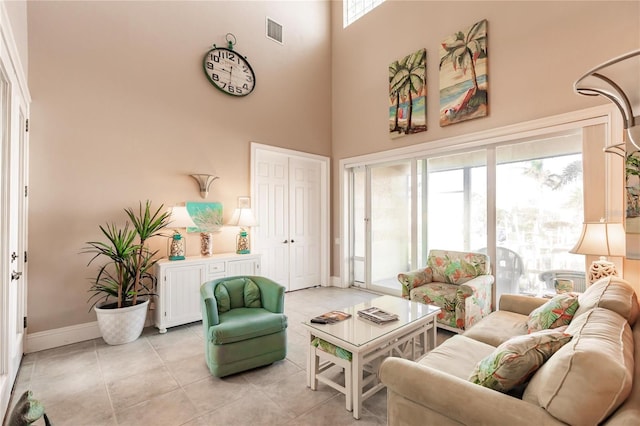 living room featuring light tile patterned floors, a towering ceiling, and plenty of natural light