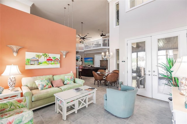 living room with tile patterned floors, french doors, ceiling fan with notable chandelier, and a high ceiling