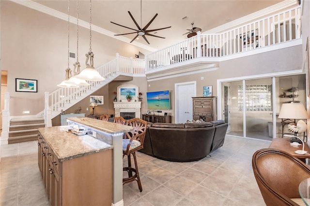 living room featuring a towering ceiling, crown molding, ceiling fan, and light tile patterned floors