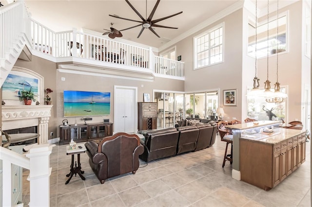 living room featuring ornamental molding, light tile patterned flooring, a high ceiling, and ceiling fan