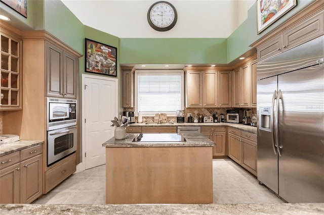 kitchen with a center island, built in appliances, decorative backsplash, and light tile patterned floors