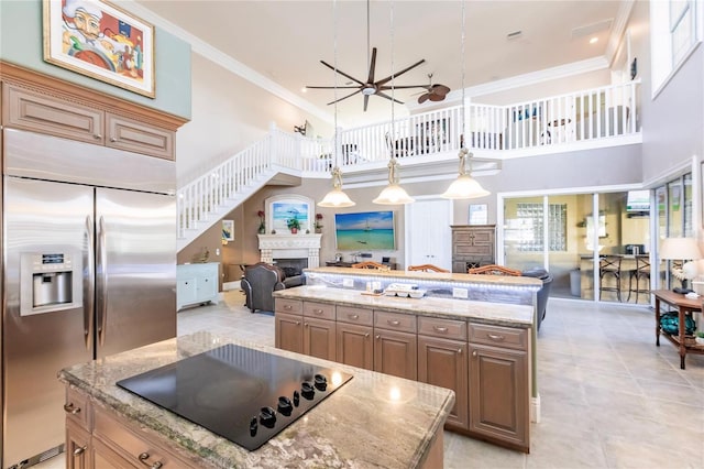 kitchen with a kitchen island, a high ceiling, black electric cooktop, built in fridge, and ceiling fan