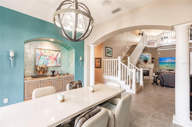 dining room featuring an inviting chandelier, ornate columns, and light tile patterned floors