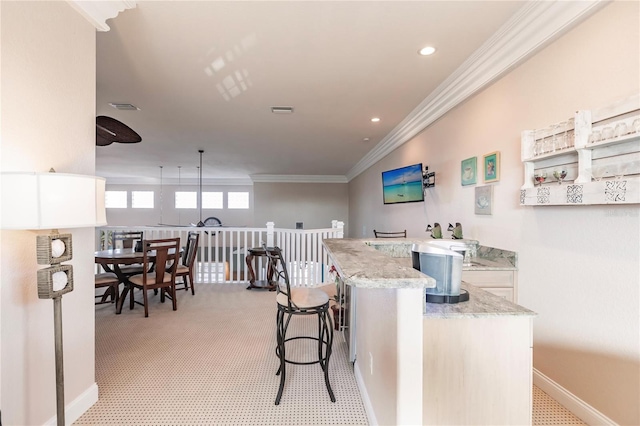 kitchen featuring white cabinets, light stone countertops, a kitchen bar, pendant lighting, and crown molding