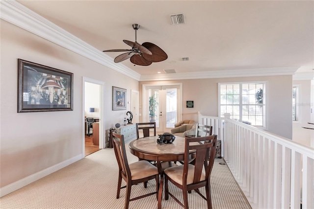 carpeted dining area with crown molding and ceiling fan