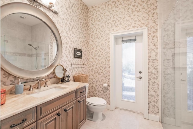 bathroom featuring vanity, a tile shower, toilet, and tile patterned floors