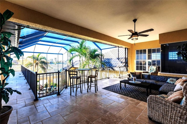 view of patio / terrace with an outdoor living space, ceiling fan, and glass enclosure