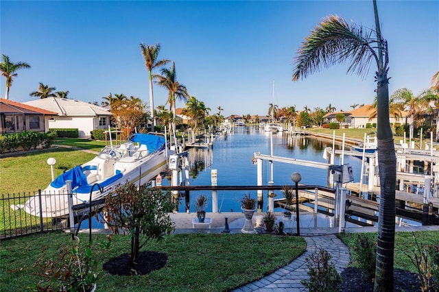 view of dock with a lawn and a water view