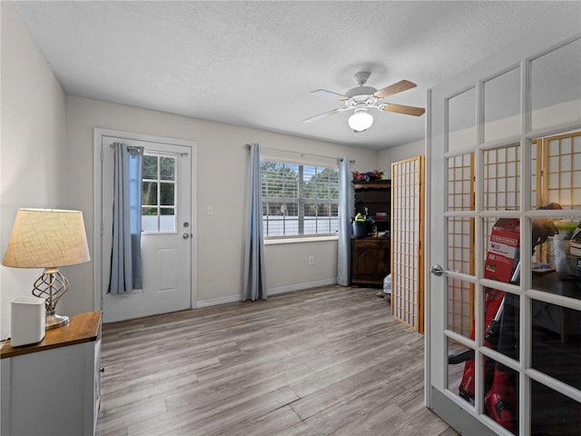 interior space with french doors, ceiling fan, light hardwood / wood-style flooring, and a textured ceiling