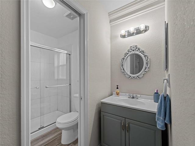 bathroom with wood-type flooring, vanity, a shower with shower door, and toilet